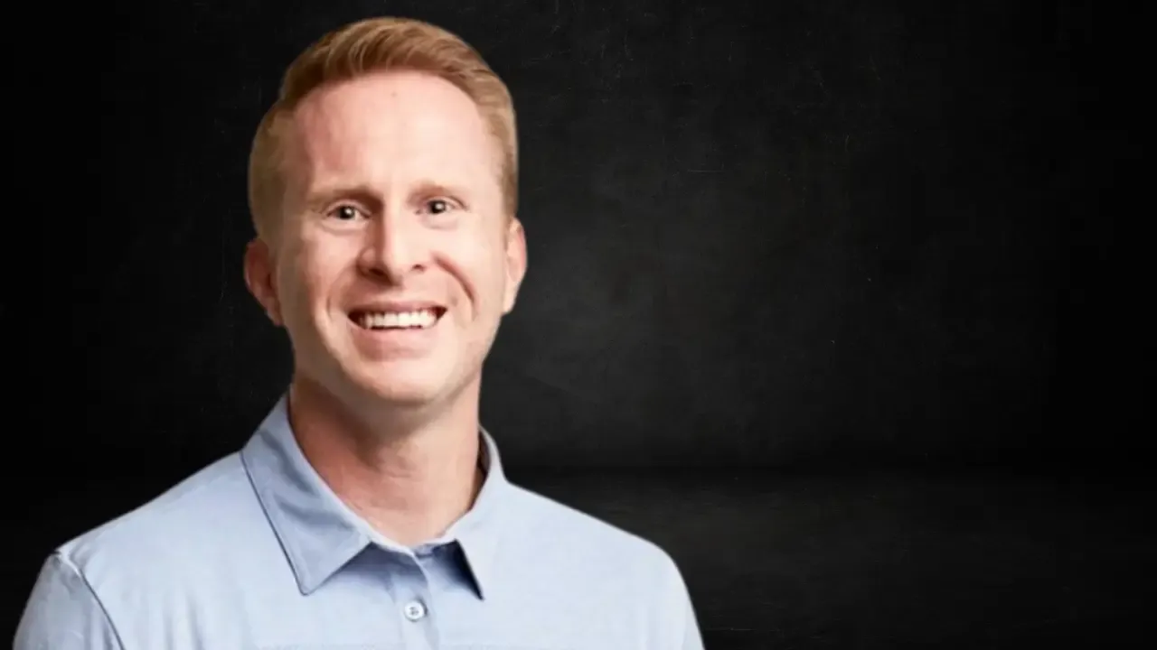 Ryan Naylor smiling in a light blue polo shirt with a dark background, years after pitching Esso Watches on Shark Tank.