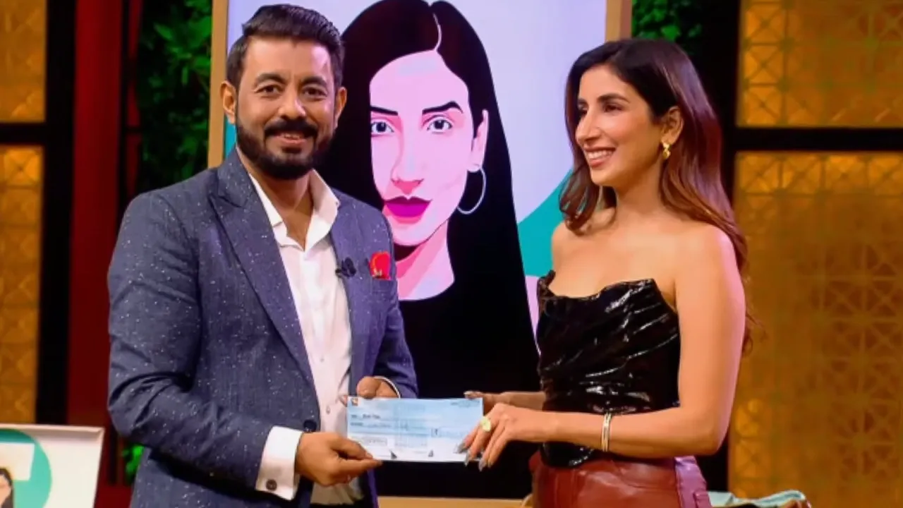 Parul Gulati on Shark Tank India receiving investment from Amit Jain for Nish Hair, holding a cheque while smiling.