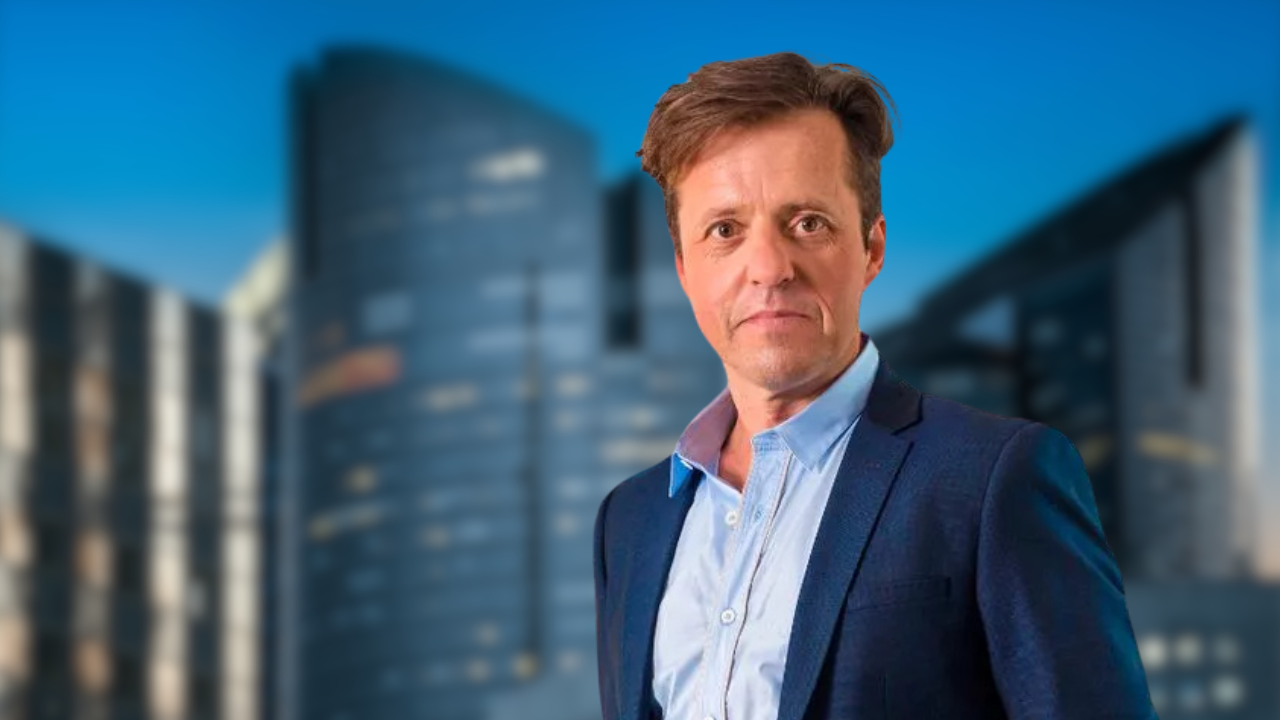 Shaun Pulfrey, founder of Tangle Teezer, wearing a blue blazer with a modern city skyline in the background.