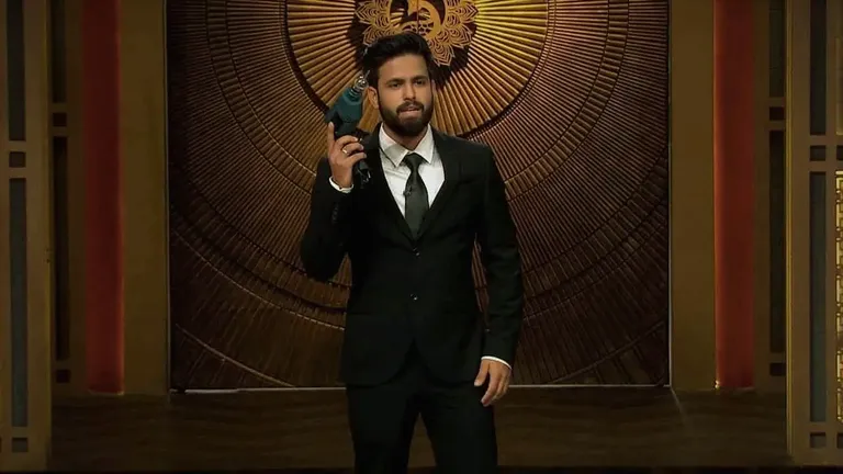 Siddharth Gupta presenting a product on Shark Tank India, wearing a black suit and holding a blue drill innovation