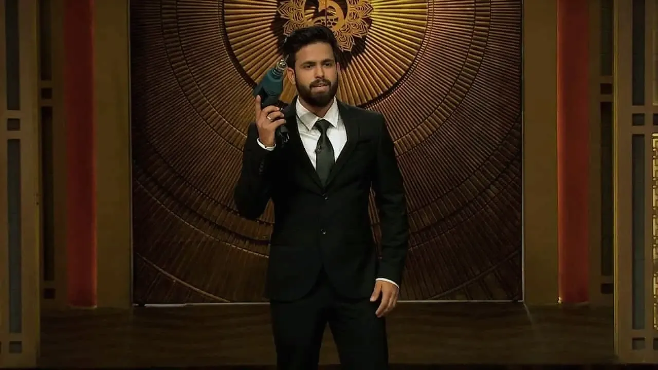 Siddharth Gupta presenting a product on Shark Tank India, wearing a black suit and holding a blue drill innovation
