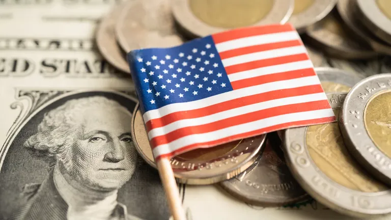 Close-up of U.S. dollar bill, coins, and American flag symbolizing millionaire growth in 2024