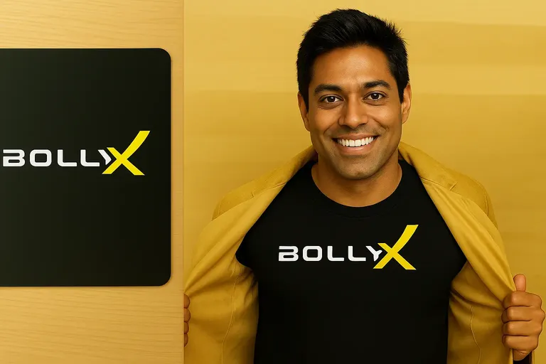 BollyX founder wearing branded t-shirt and gold jacket next to BollyX logo on wooden background