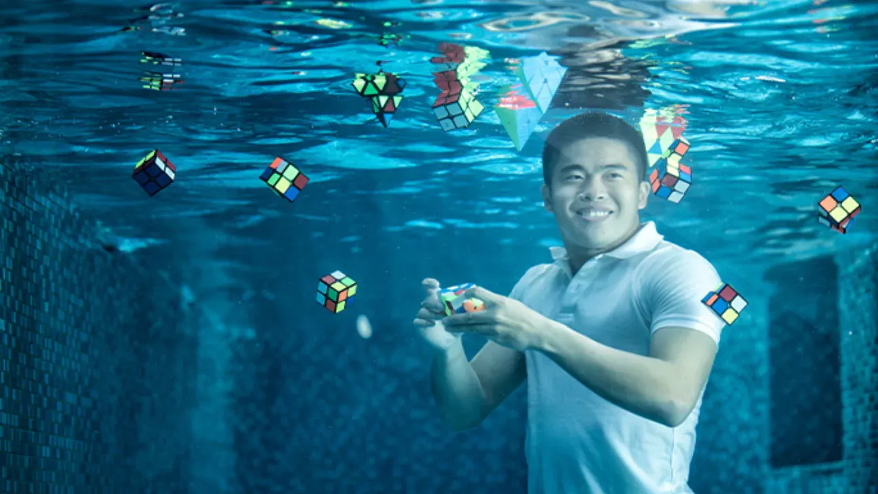 A man solving a Rubik’s Cube underwater surrounded by floating cubes, representing a Guinness World Record feat by Daryl Tan in 2023.