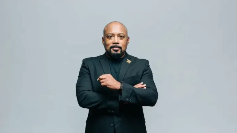 Daymond John standing confidently in a black suit, sharing daily habits of successful entrepreneurs.