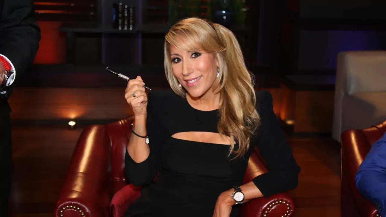 Lori Greiner sitting in Shark Tank studio holding a pen, sharing tips to get products into major retail stores like Target and Walmart