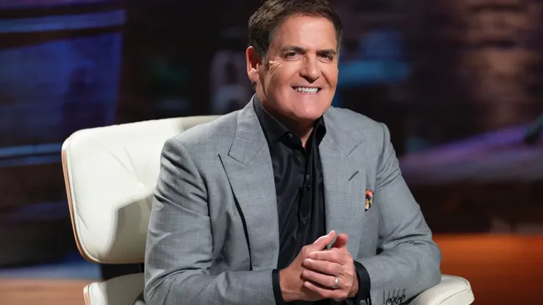 Mark Cuban smiling in a gray suit during a Shark Tank episode, known for investing in Relativity Space via cold email.