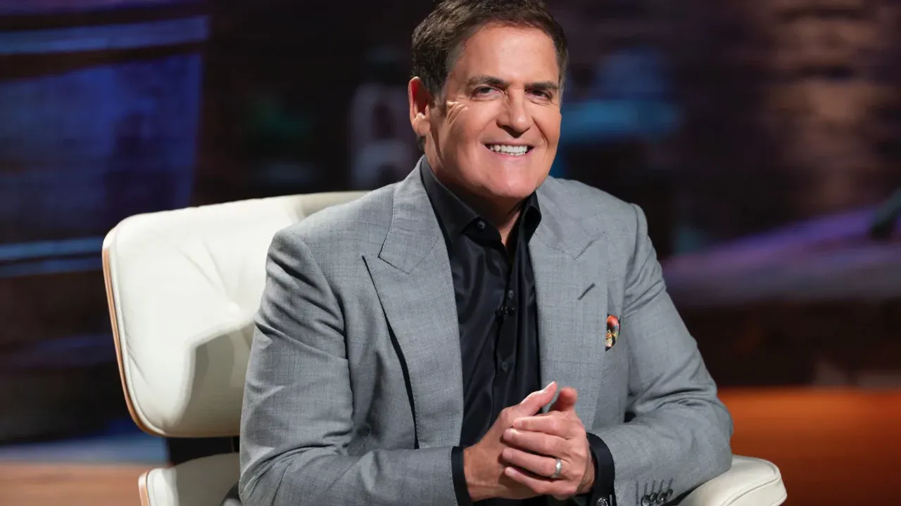 Mark Cuban smiling in a gray suit during a Shark Tank episode, known for investing in Relativity Space via cold email.