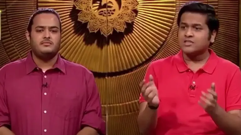 PlayboxTv co-founders presenting their OTT aggregation platform on Shark Tank India with a golden backdrop behind them.